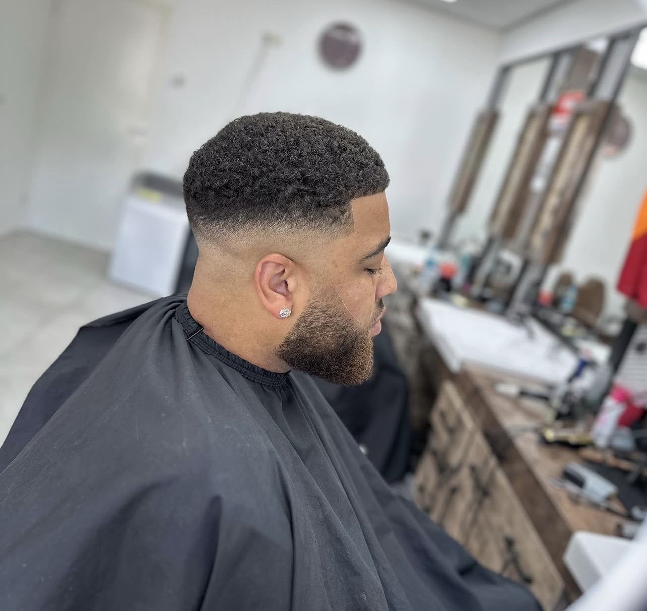 Krullen bovenop met een fade en een volle baard, van opzij
